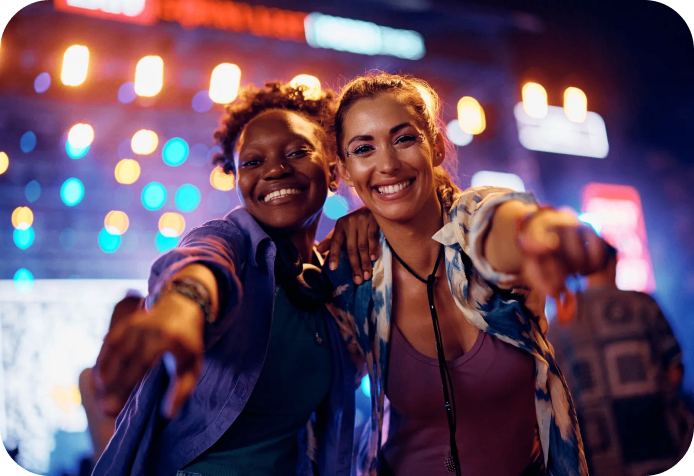 Two friends smiling at a concert.